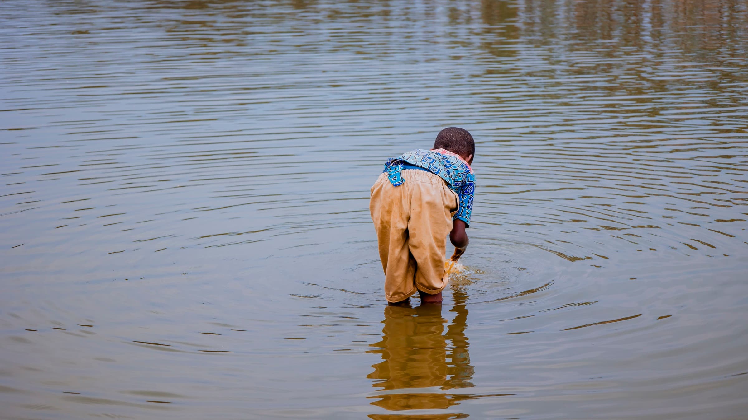 A child in the shallows of a Gashora water source.