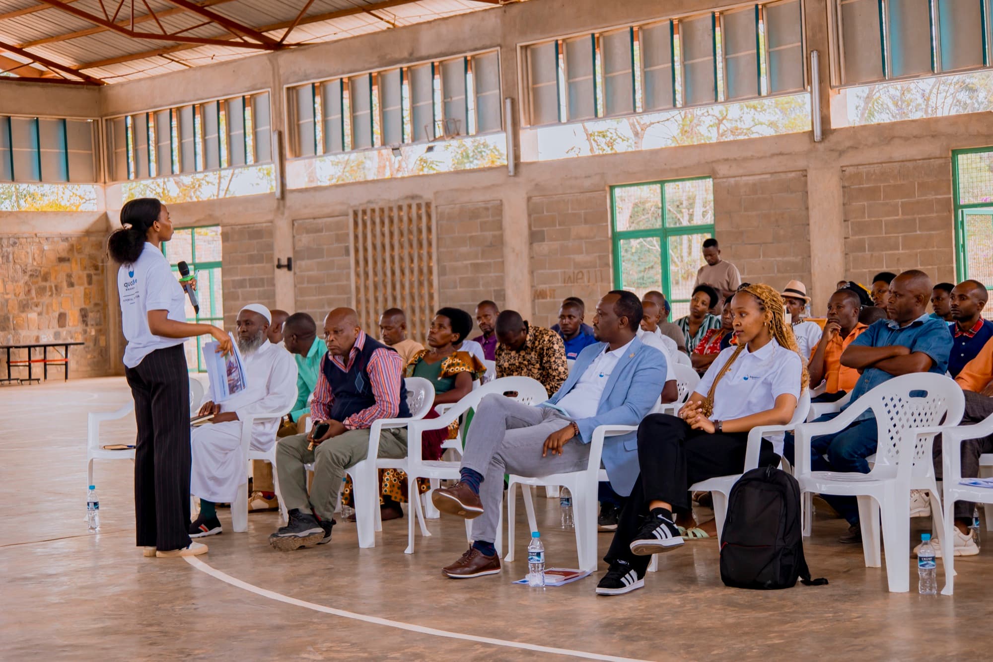 The SAquaSolve team addressing a full community hall during a WASH workshop in Gashora.